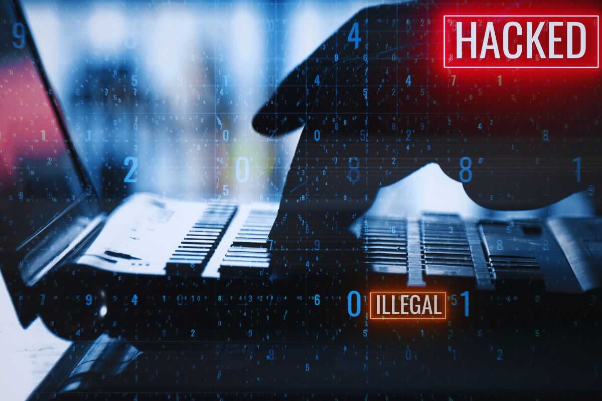 Mani su tastiera di un laptop e scritta "Hacked"