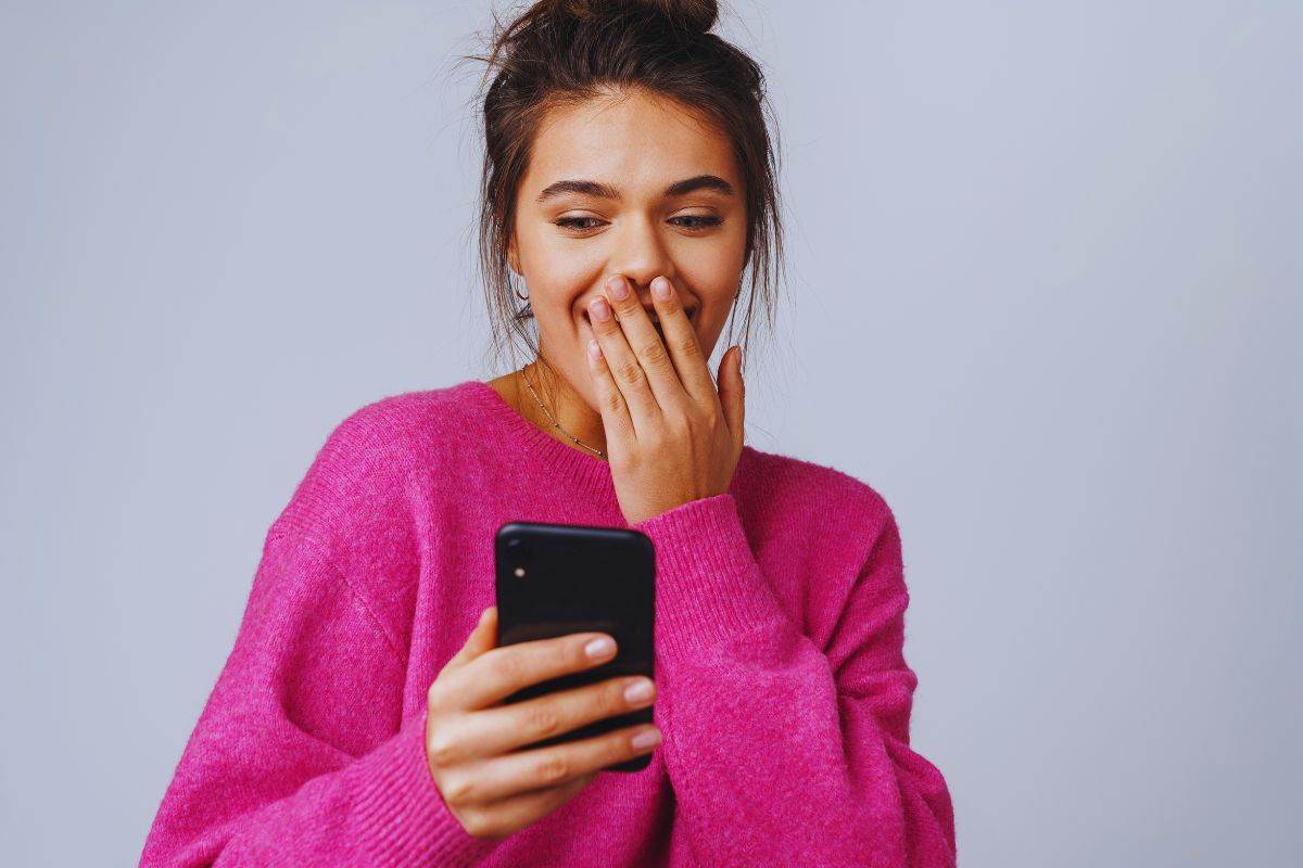 Ragazza con espressione sorpresa mentre guarda smartphone