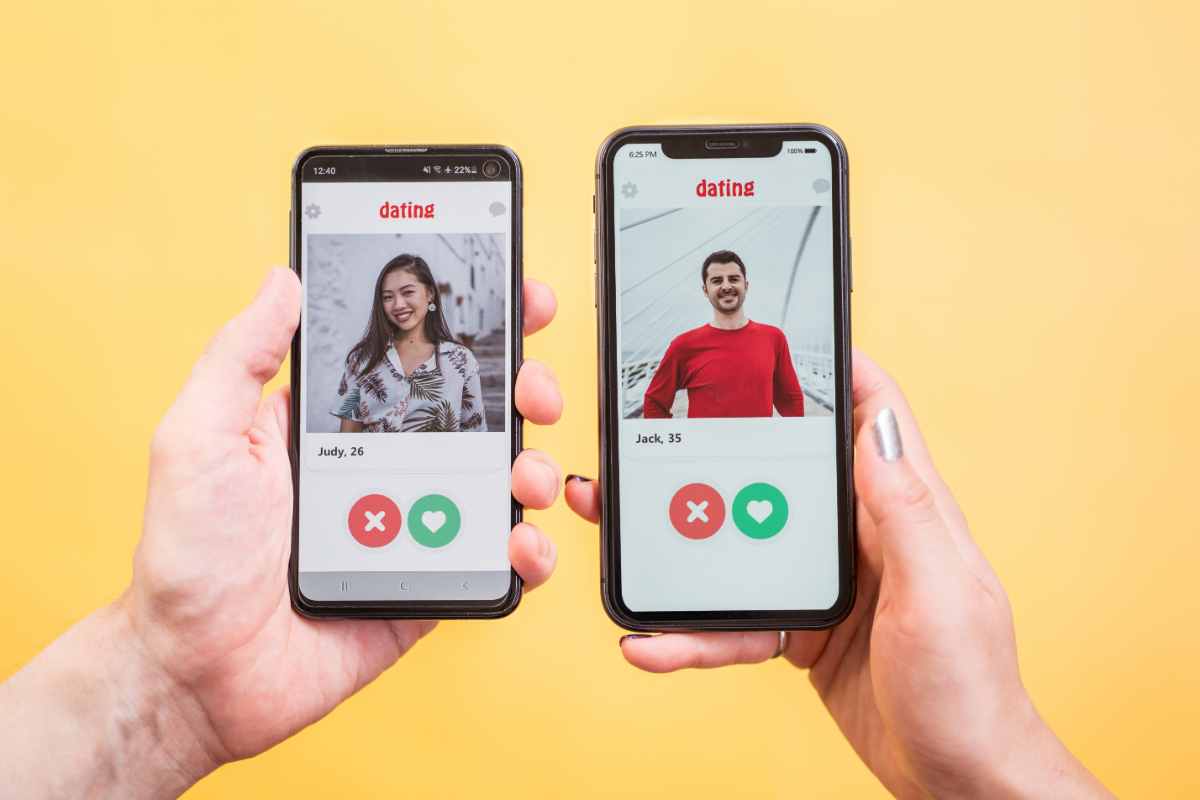 mani con smartphone sul cui schermo ci sono profili di persone che usano app di incontri