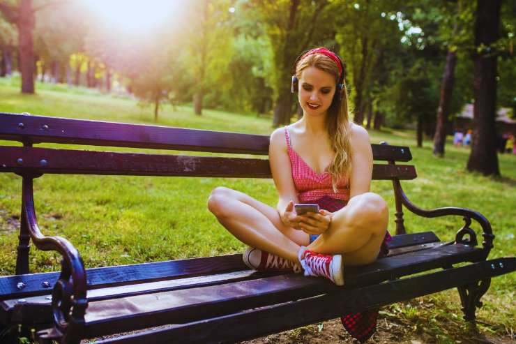Ragazza che ascolta musica su una panchina di un parco