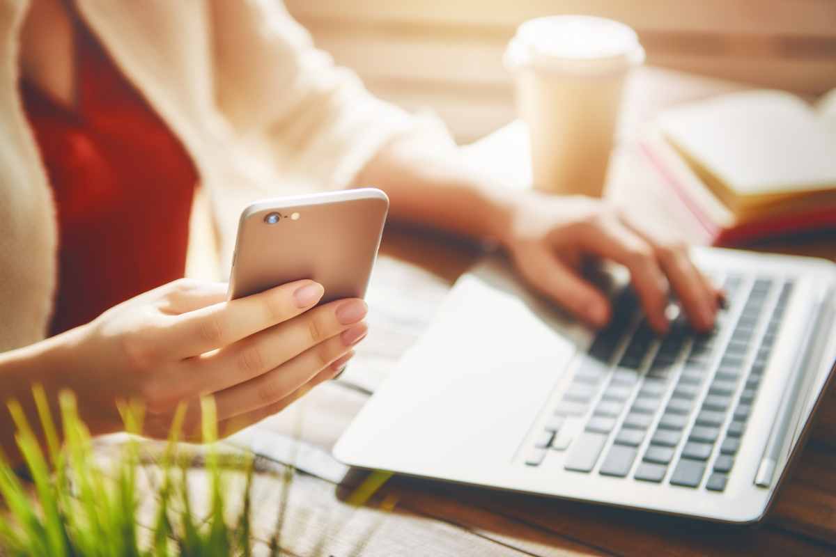 donna con cellulare in mano e pc portatile usato per spiare