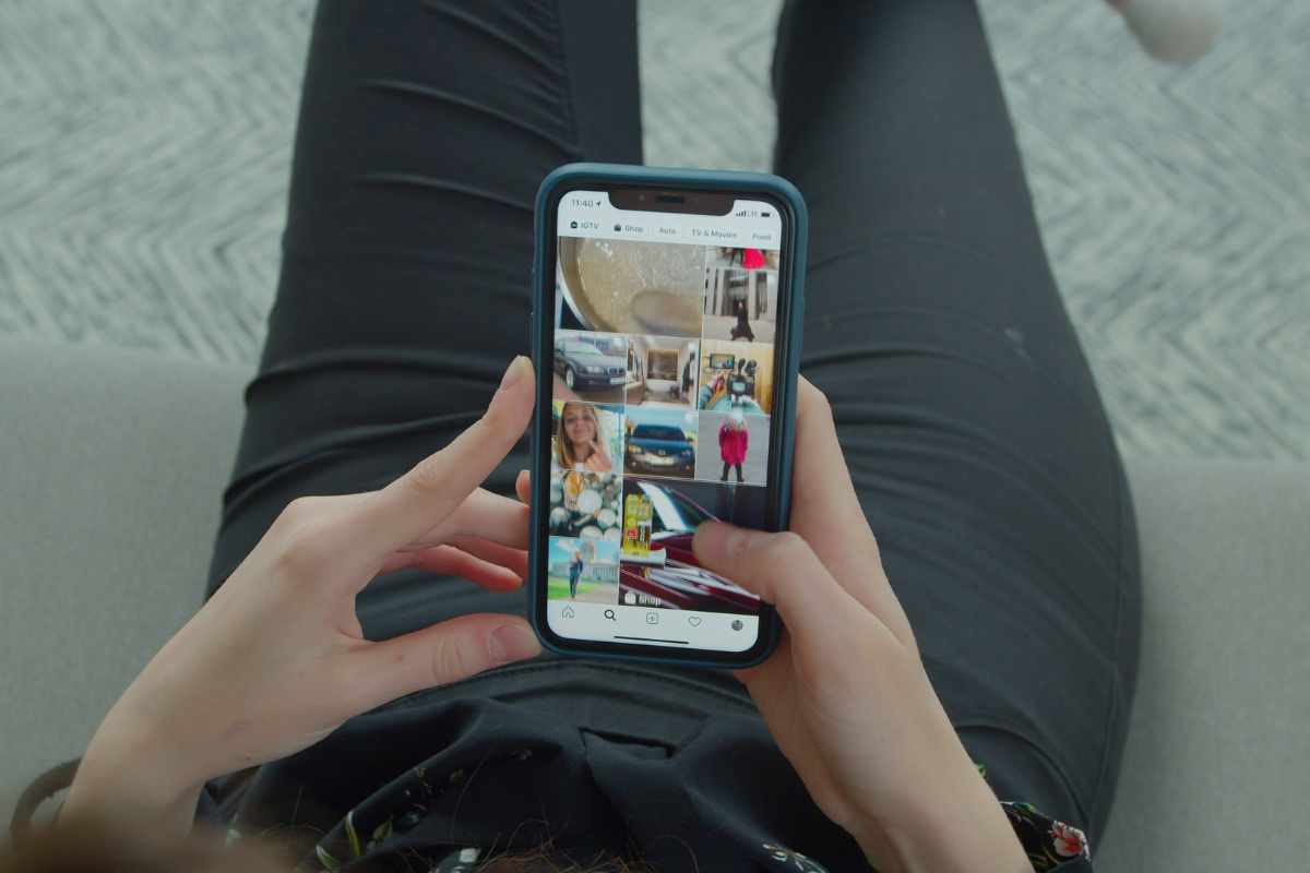mani che usano uno smartphone su cui si vedono delle foto
