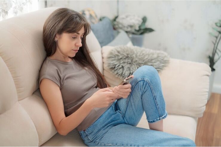 Ragazza sul divano usa cellulare 