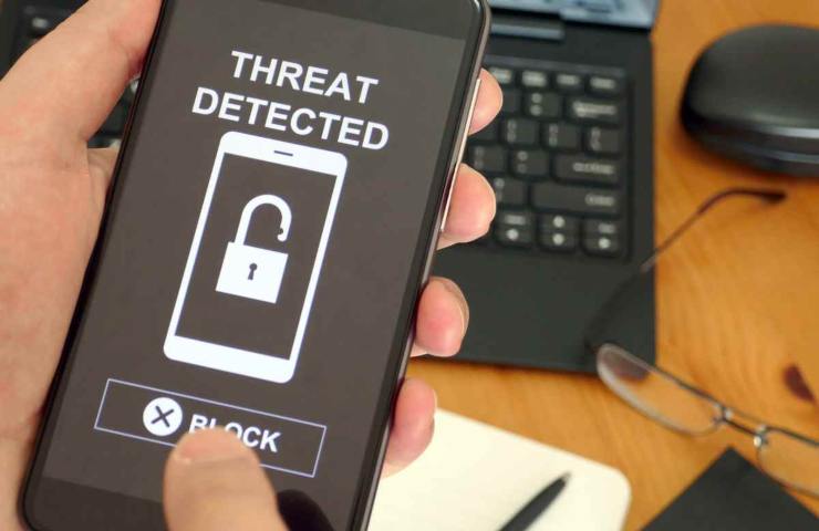 mano che usa un telefono con minaccia rivelata scritto sopra