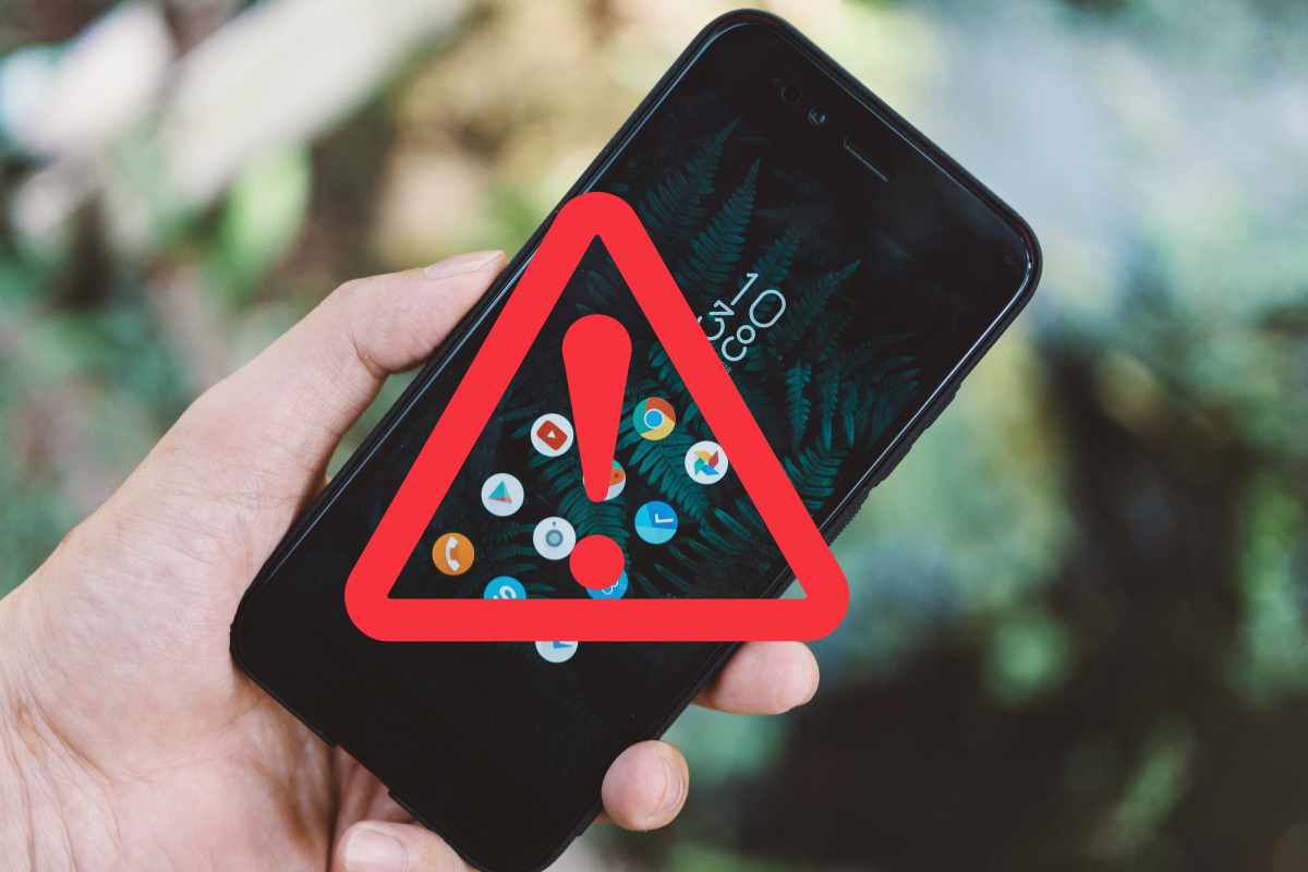 mano che tiene uno smartphone con triangolo di pericolo