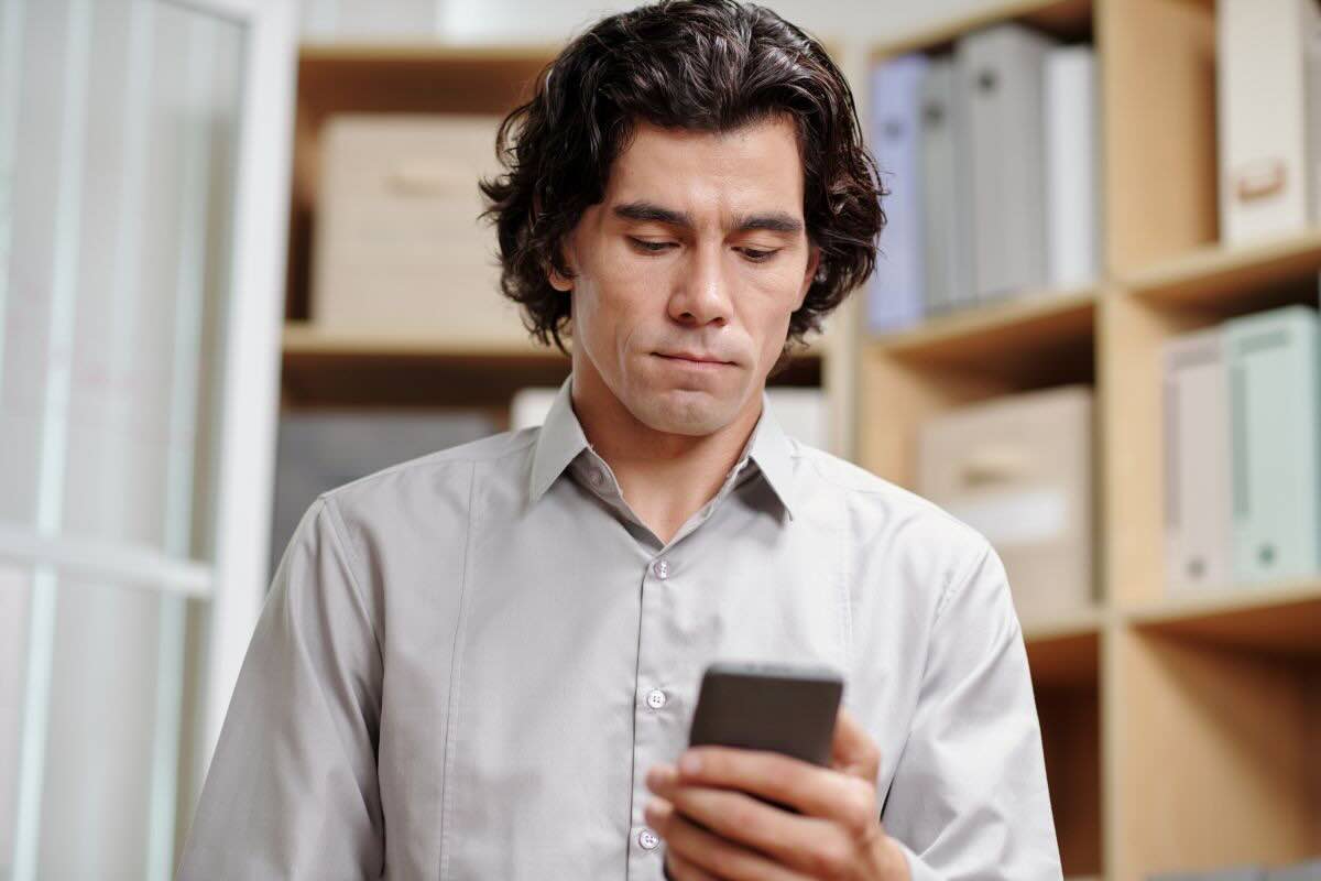 Uomo legge messaggio sul suo cellulare