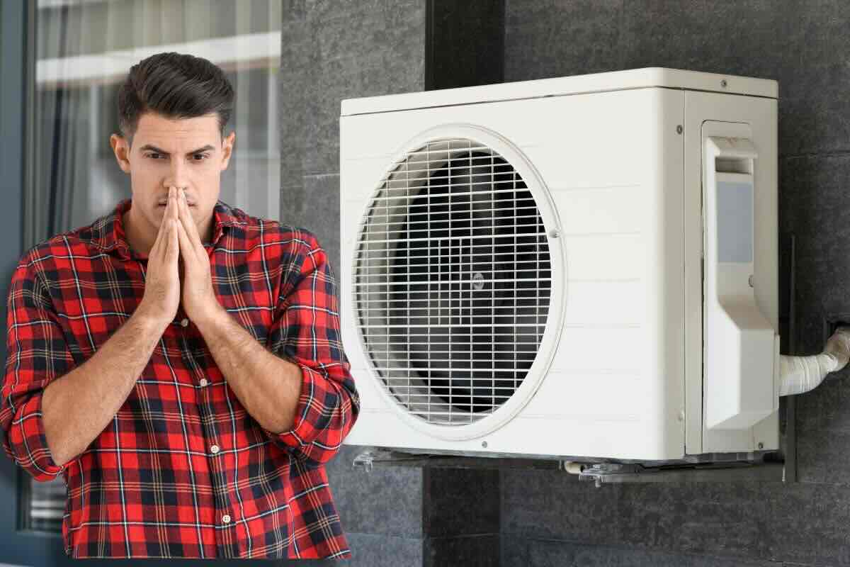 Condizionatore, uomo preoccupato mani giunte sul viso