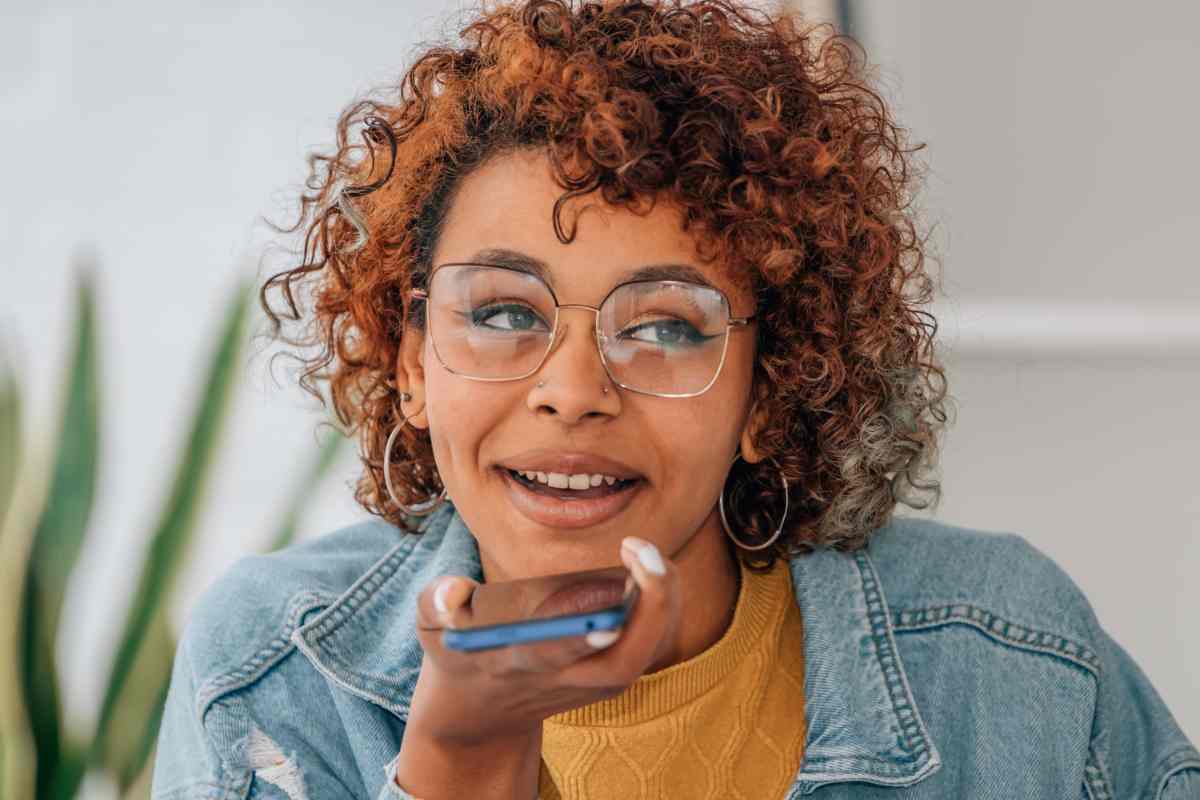 ragazza con smartphone in mano effettua una chat vocale di gruppo su WhatsApp