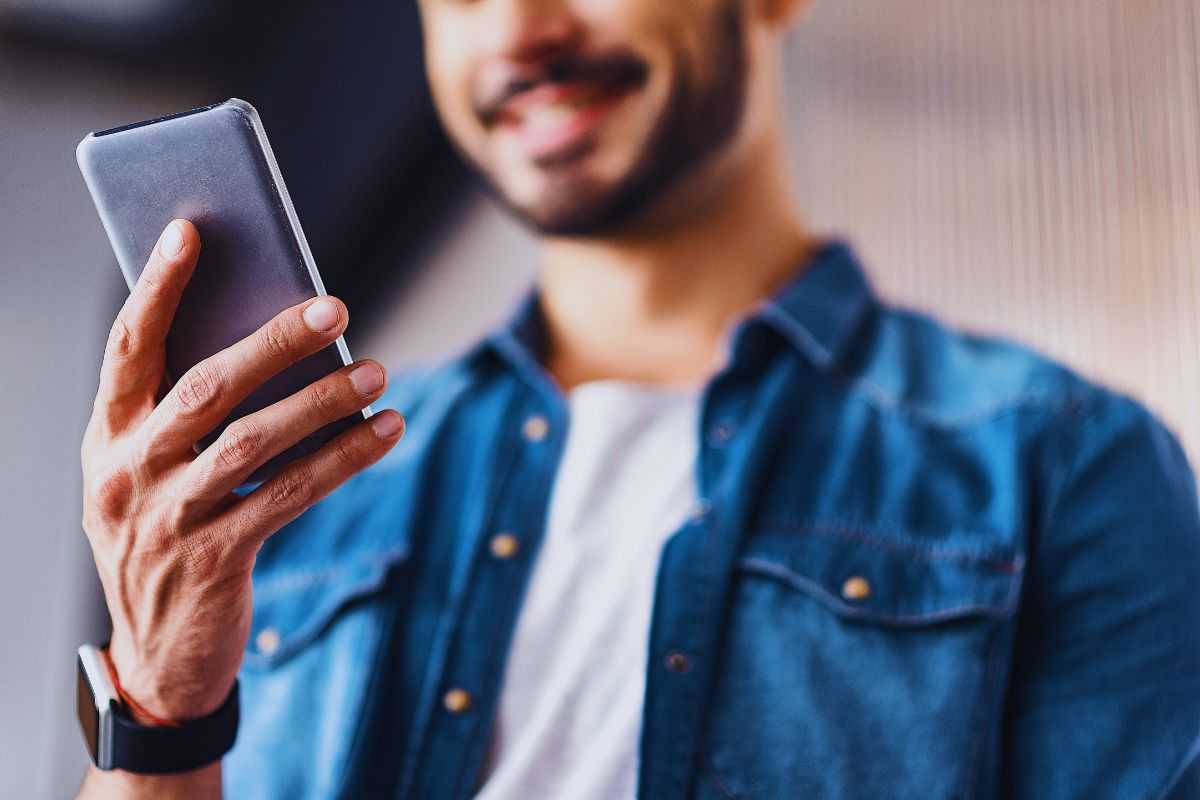 Ragazzo sorridente mentre legge messaggi su smartphone