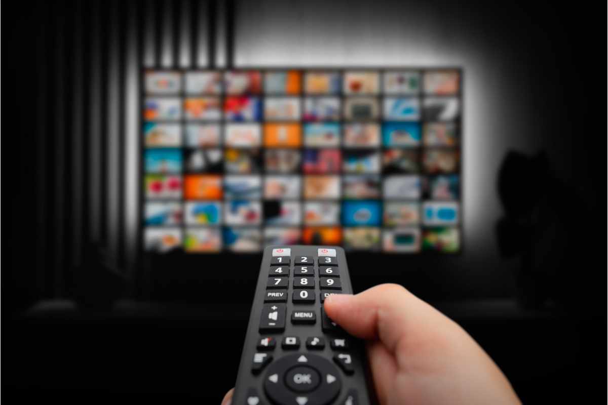 mano sul telecomando rivolto verso la tv smart