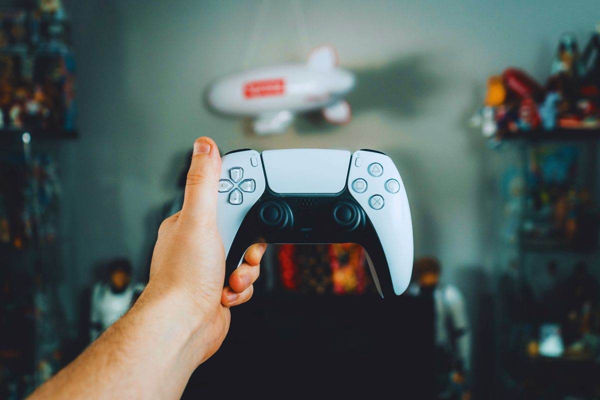 persona che tiene in mano un controller PS5