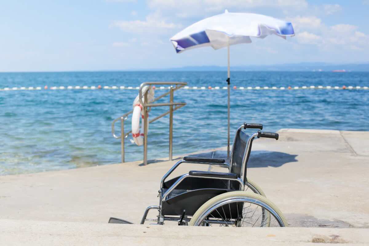 Carrozzina in spiaggia con ombrellone bianco e azzurro