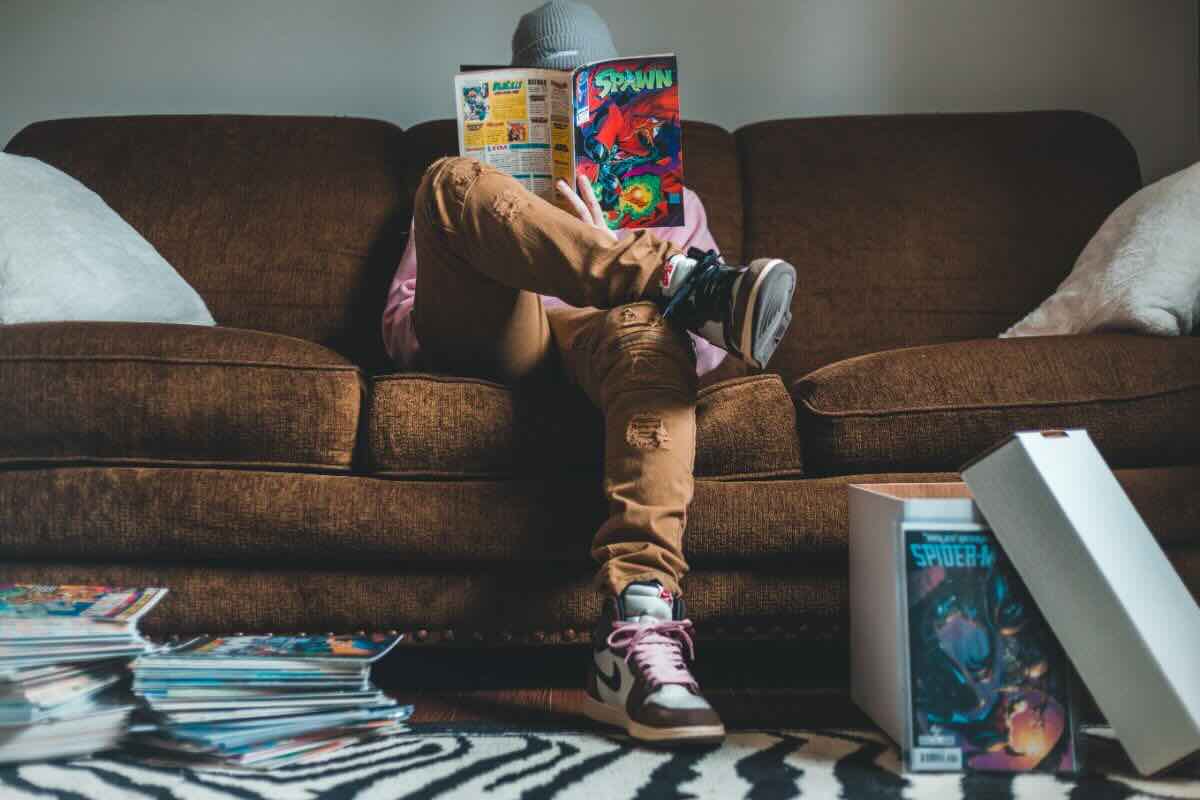 Ragazzo seduto sul divano legge fumetto