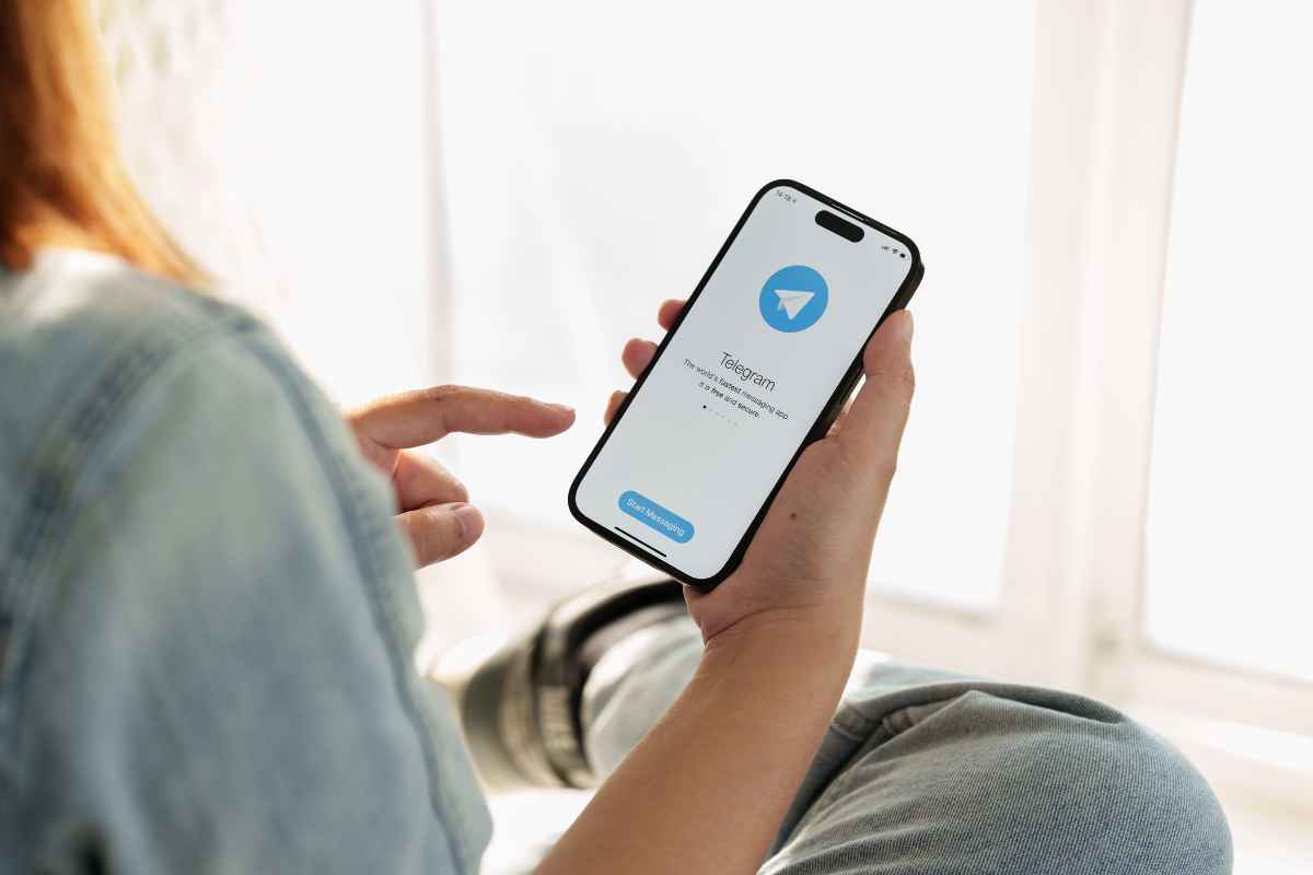 mani che usano telegram su un telefonino