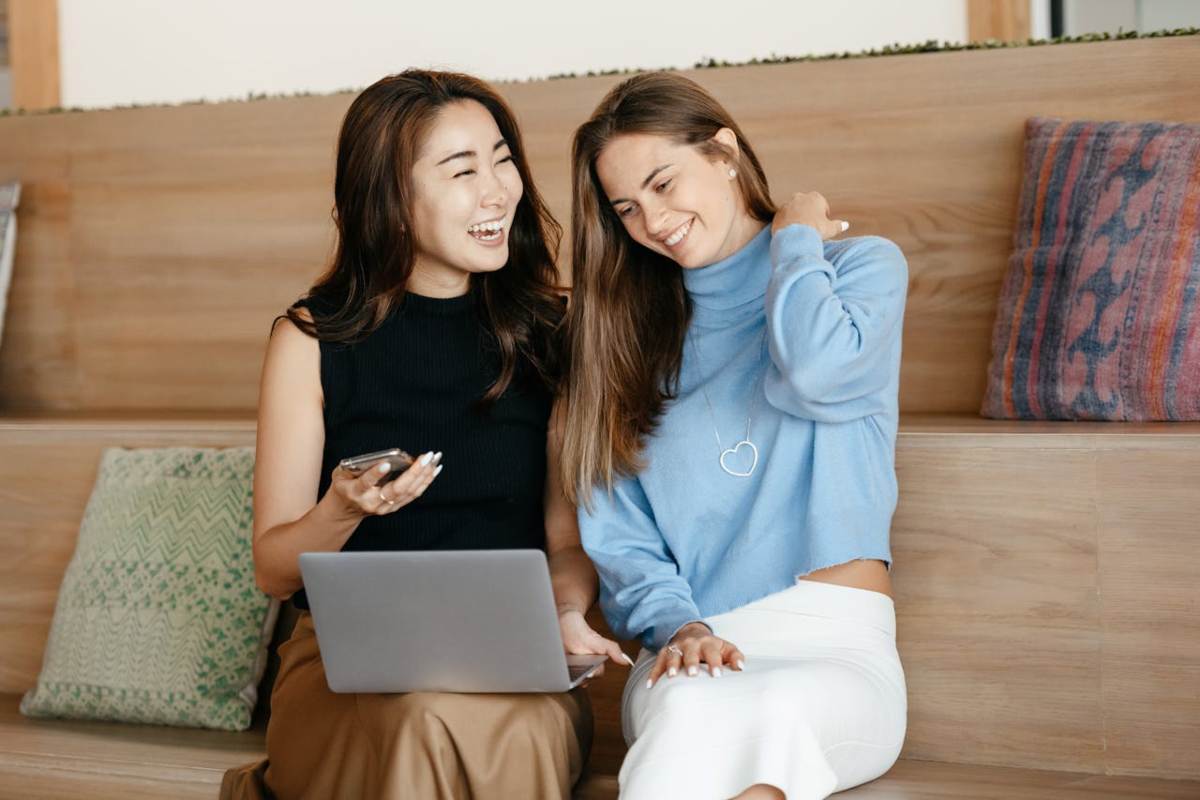 Donne che ridono guardando laptop e smartphone