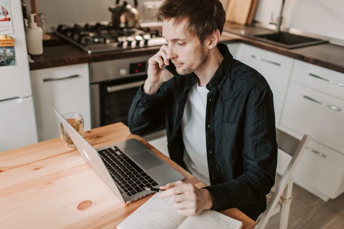 uomo al pc con il telefono