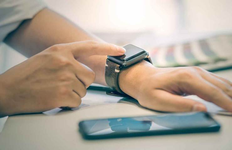 uomo usa smartwatch e telefono