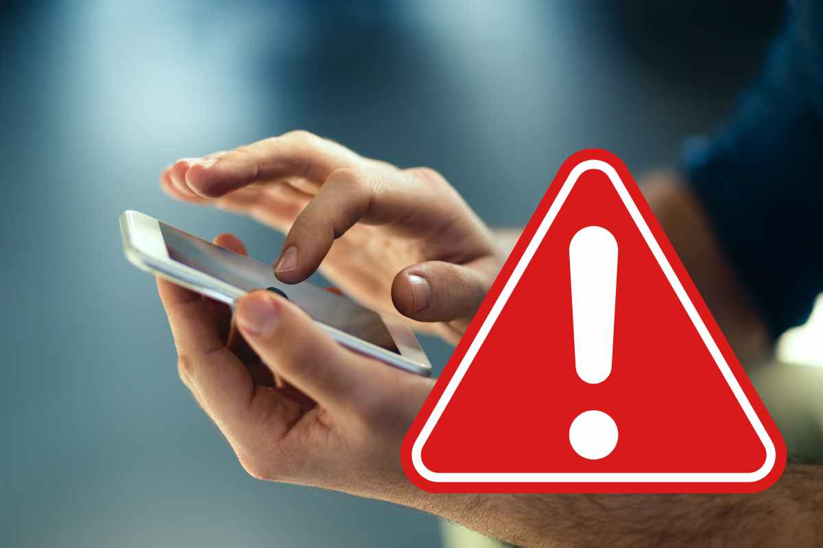 mani telefono con simbolo di pericolo