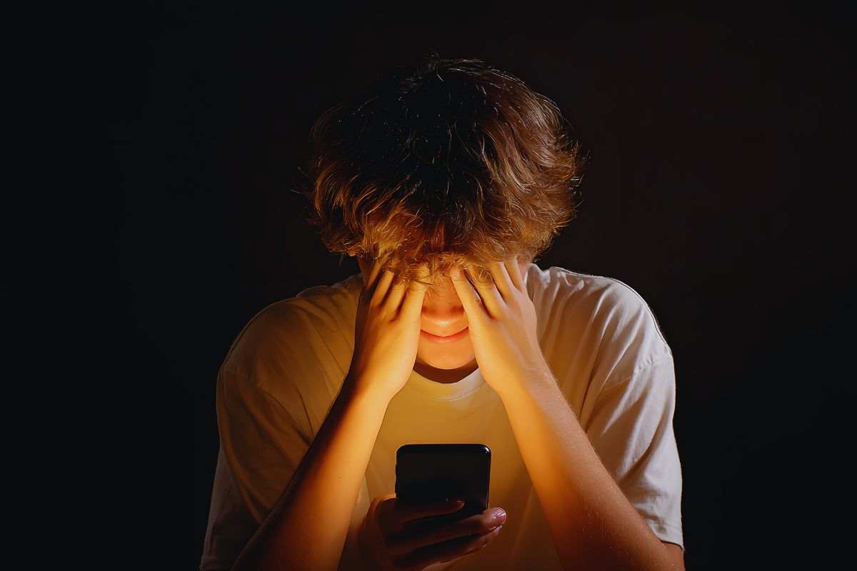 Ragazzo con le mani davanti agli occhi in segno di disperazione