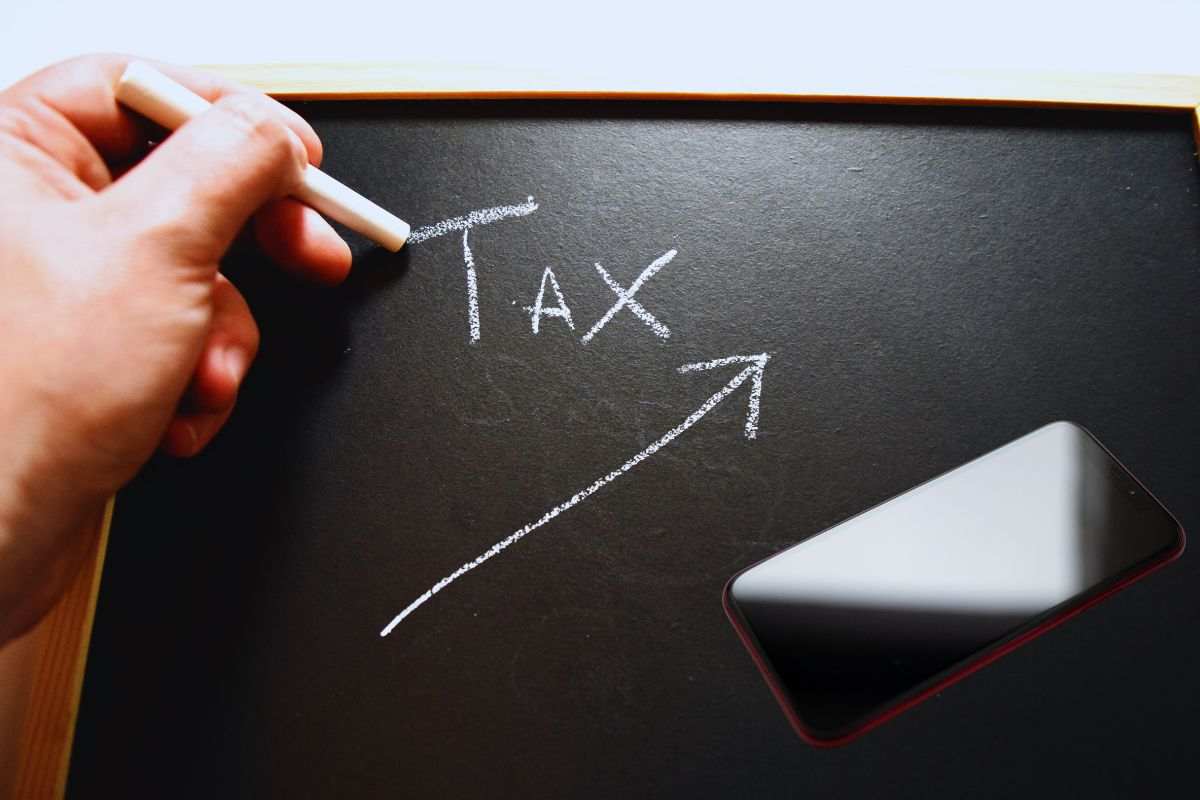 Smartphone e lavagna su cui viene segnalato l'aumento delle tasse