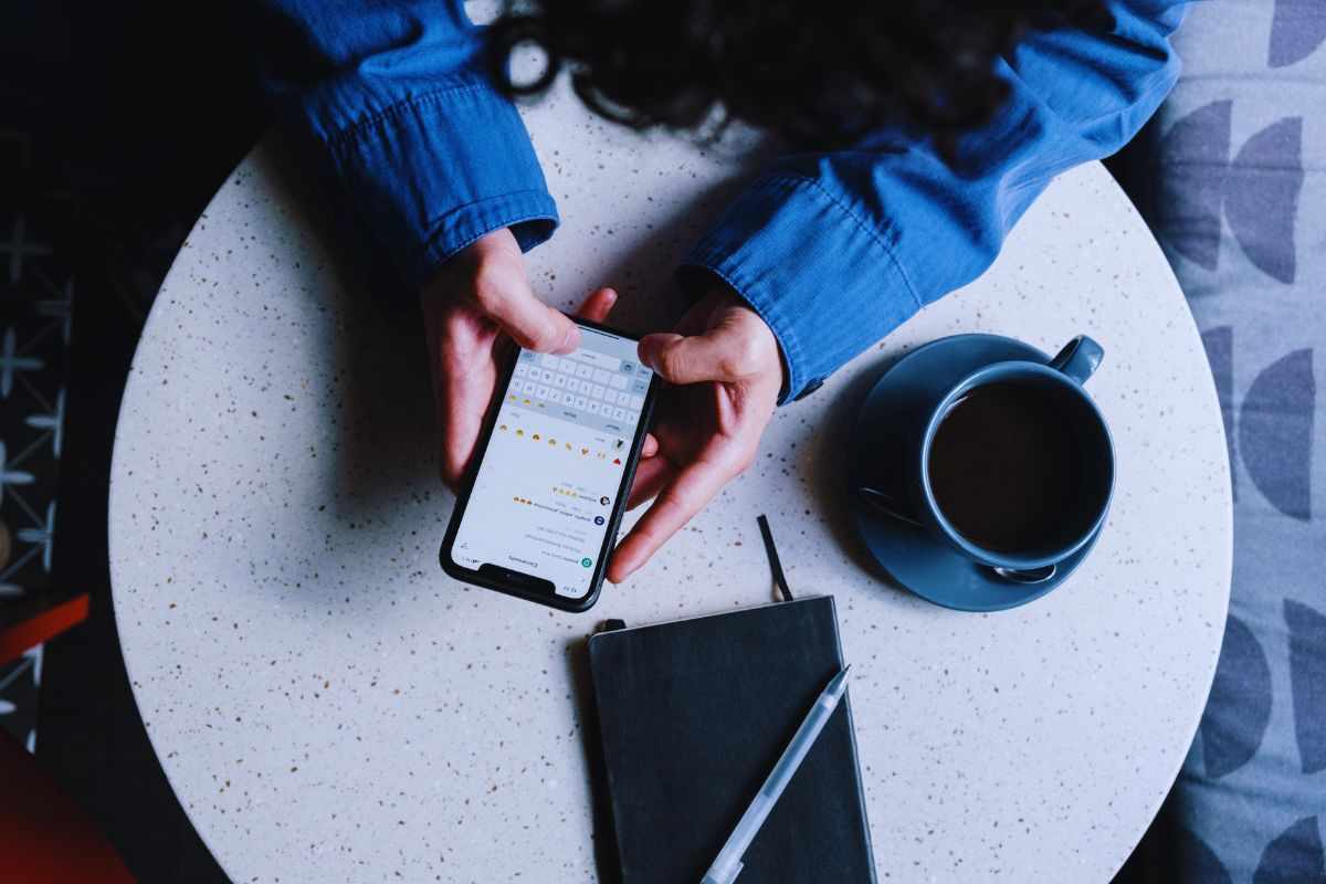 Ragazza seduta al bar che chatta con lo smartphone