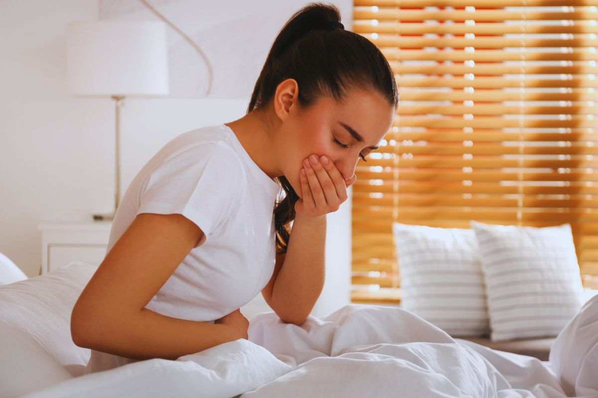Donna a letto con la nausea