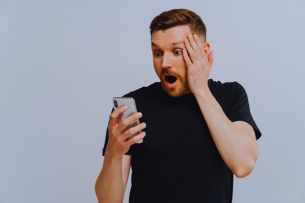 Uomo sorpreso da ciò che vede sullo smartphone