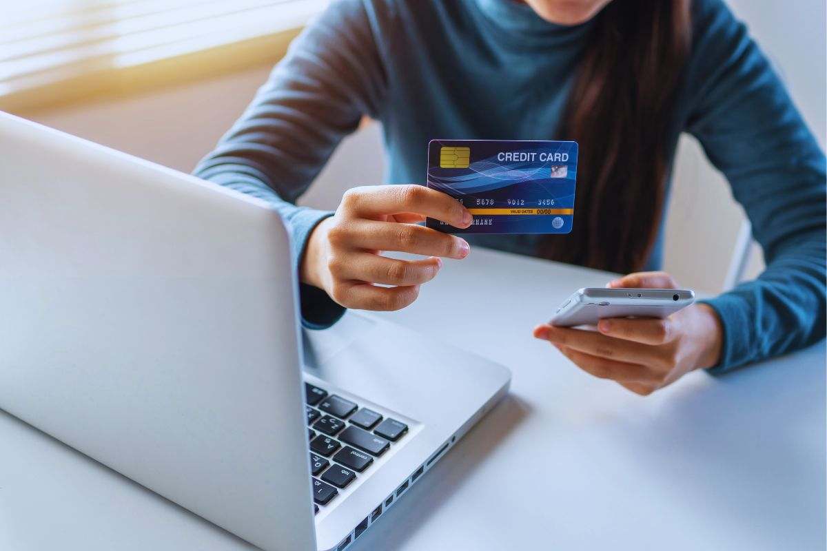 Ragazza con telefono in una mano e carta di credito nell'altra