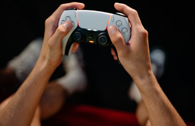 Un pad DualSense di PlayStation bianco tra le mani di una persona 5