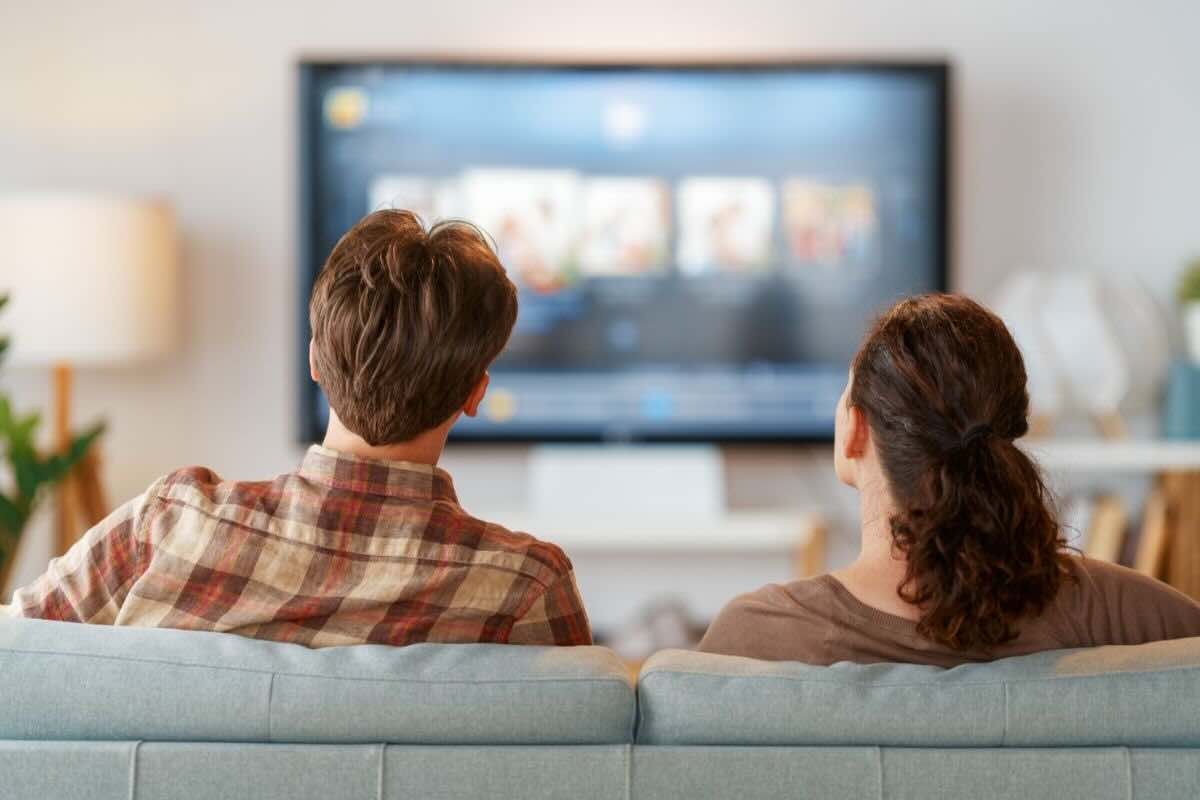 Coppia sul divano guarda TV