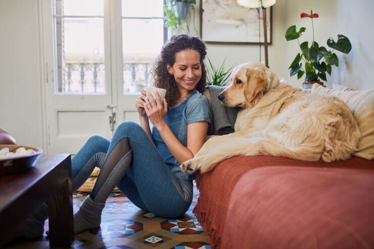 Donna seduta sul pavimento, cane sul divano