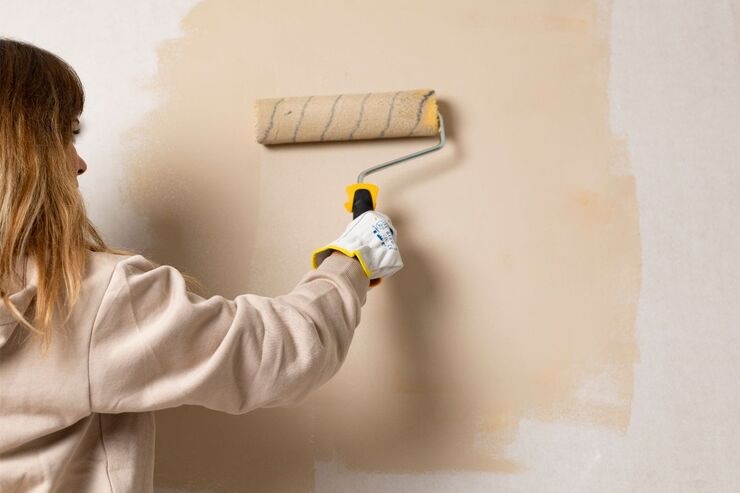 Donna che tinge parete di beige 