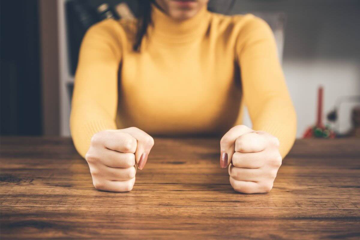 Donna con pugni chiusi che batte sul tavolo