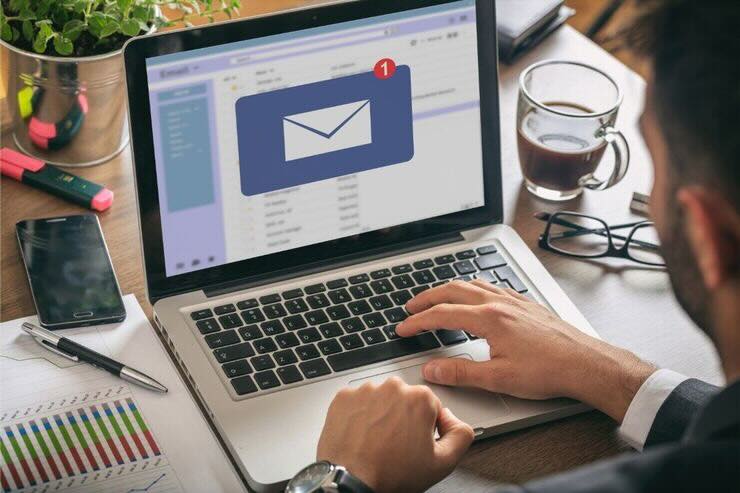 Uomo scrive al PC, nuova mail in arrivo