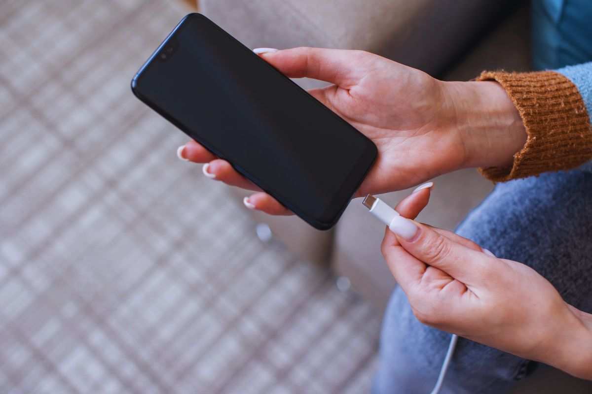 Donna che collega smartphone a caricabatteria