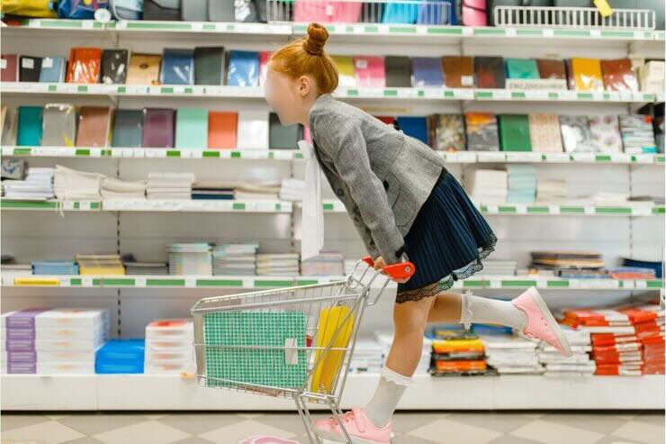 Bambina su carrello nel negozio di articoli scolastici