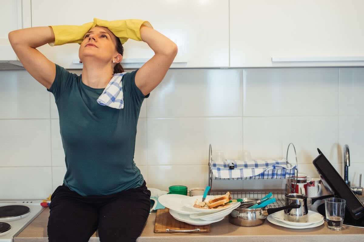 Donna mani sul capo stressata, cucina disordinata