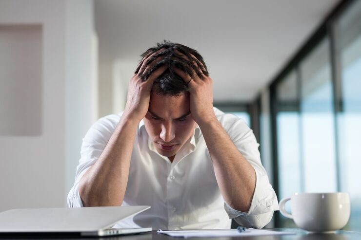 Ragazzo con mani sul capo alla scrivania 