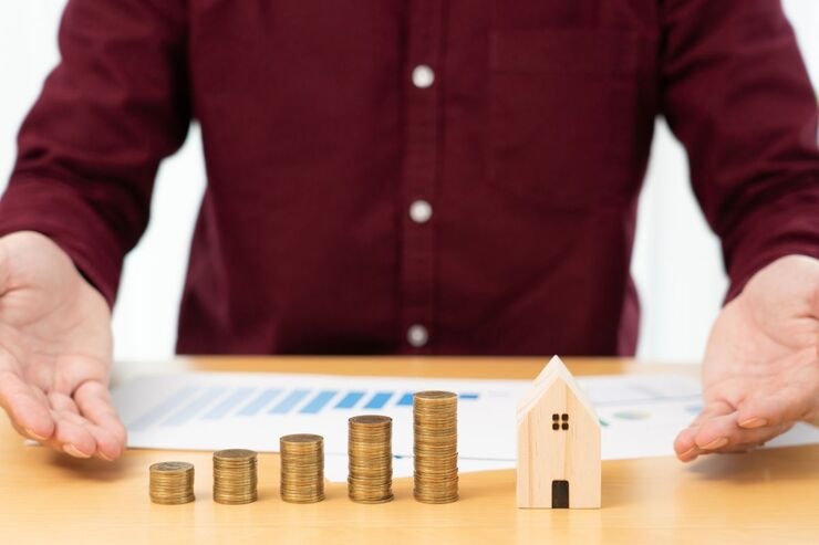 Monete, casetta in legno, uomo legge documento con grafico