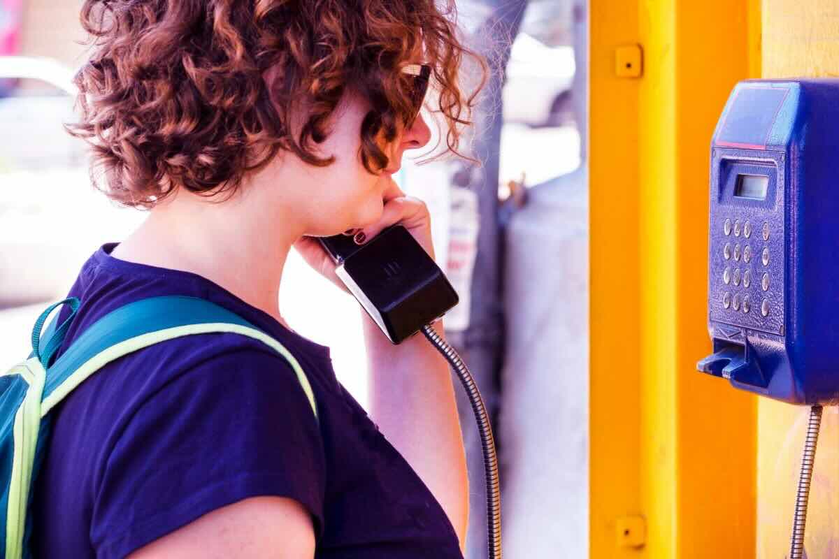 Donna parla alla cabina telefonica