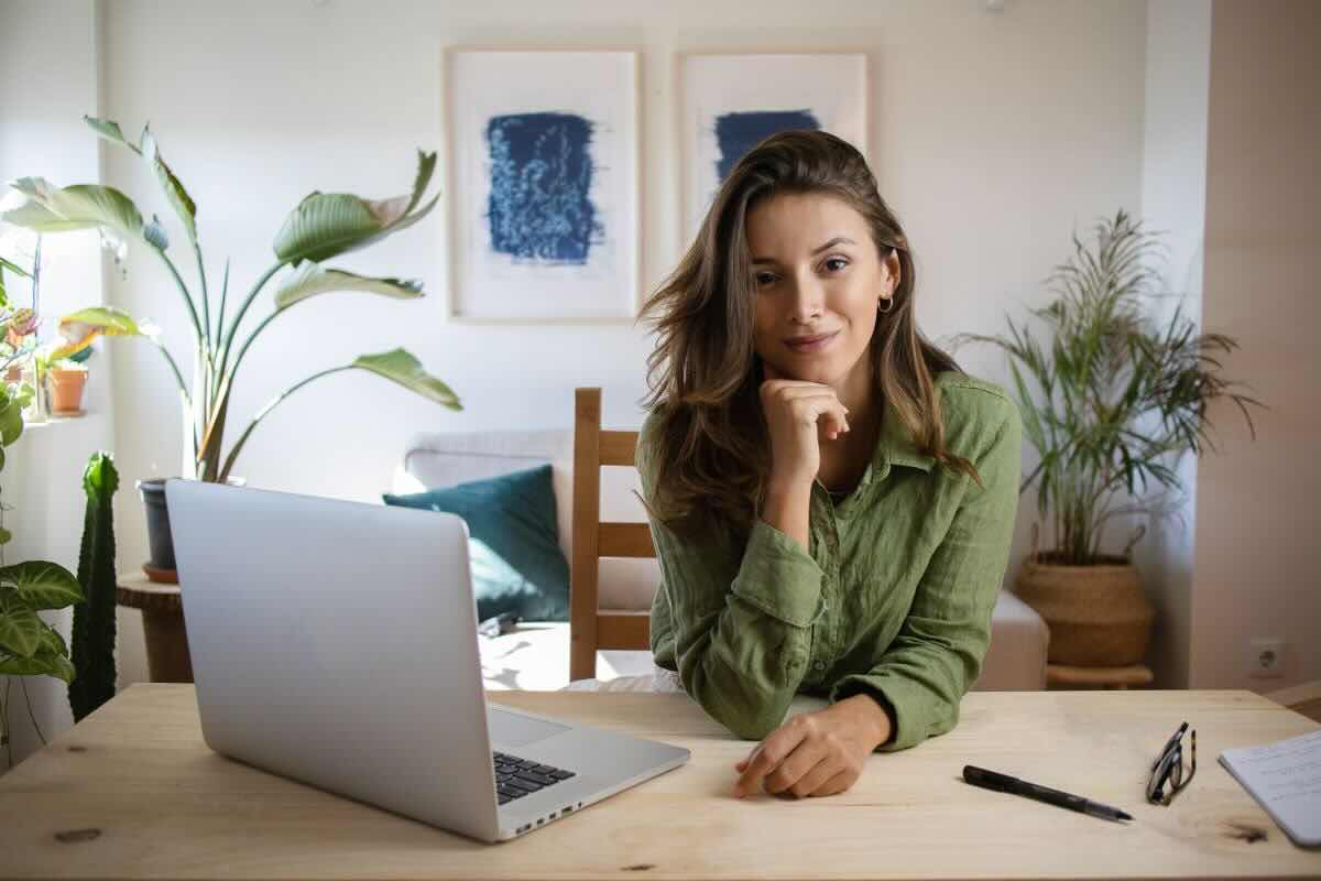 Ragazza alla scrivania con PC di fianco, soddisfatta