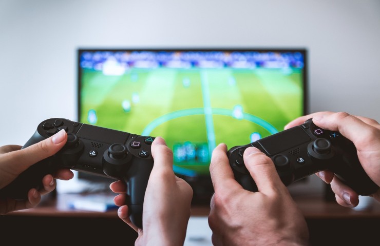 Mani di uomo e di donna che tengono dei pad davanti alla tv