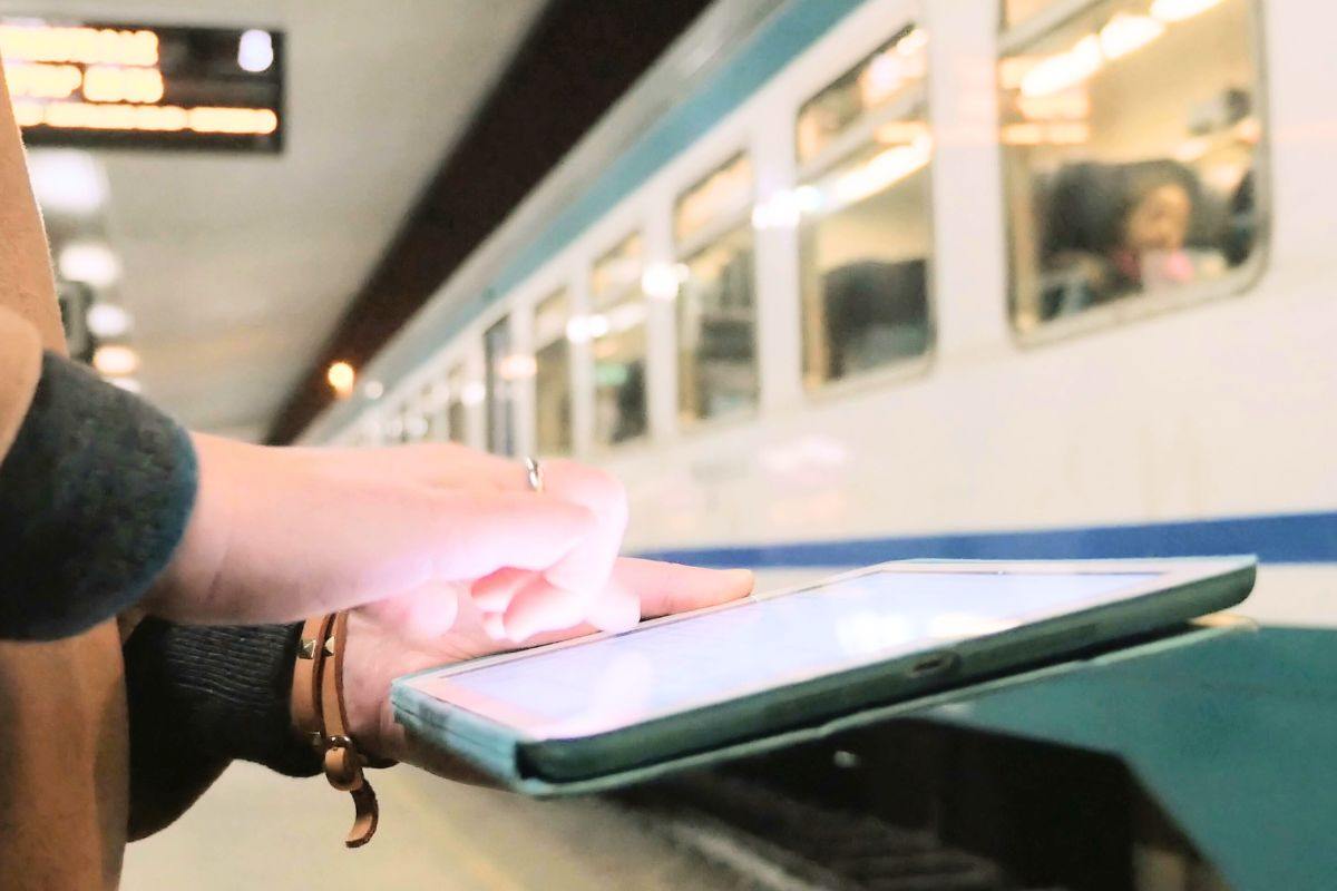 Donna consulta il suo tablet alla stazione ferroviaria
