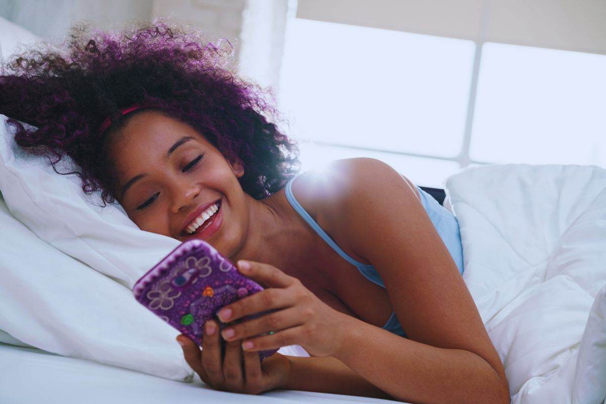 Ragazza che sorride mentre usa lo smartphone