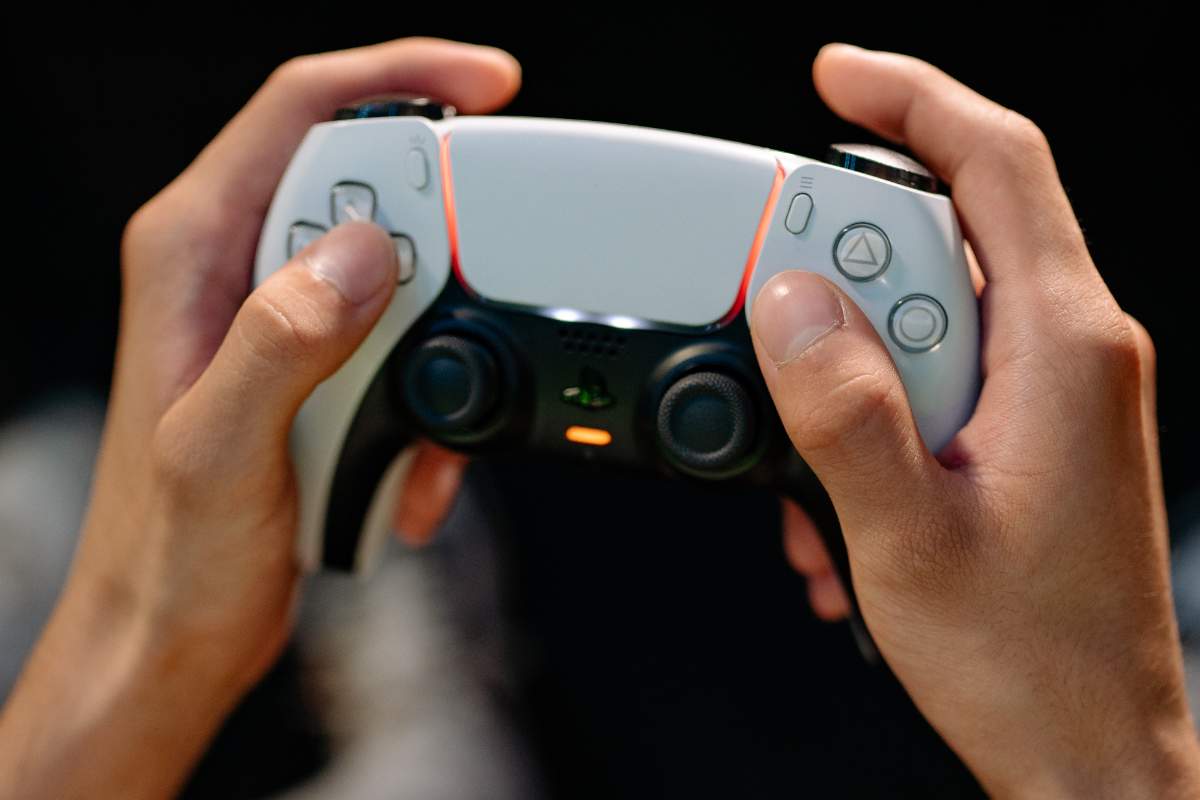 Due mani che tengono un pad PS5 DualSense