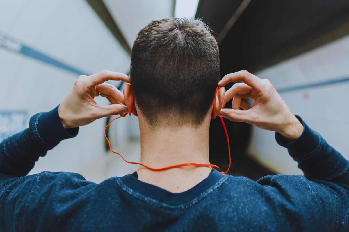 Ragazzo che sistema gli auricolari mentre cammina nella metro