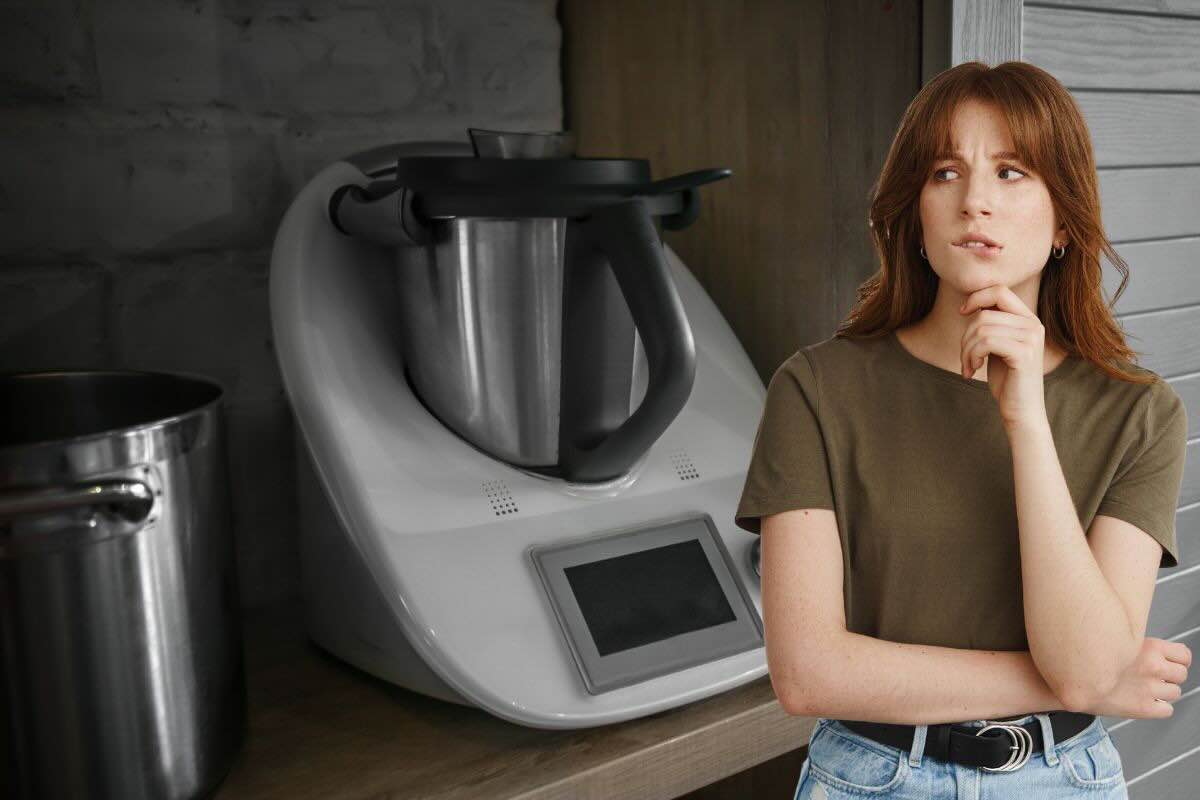 Ragazza pensierosa vicino robot da cucina