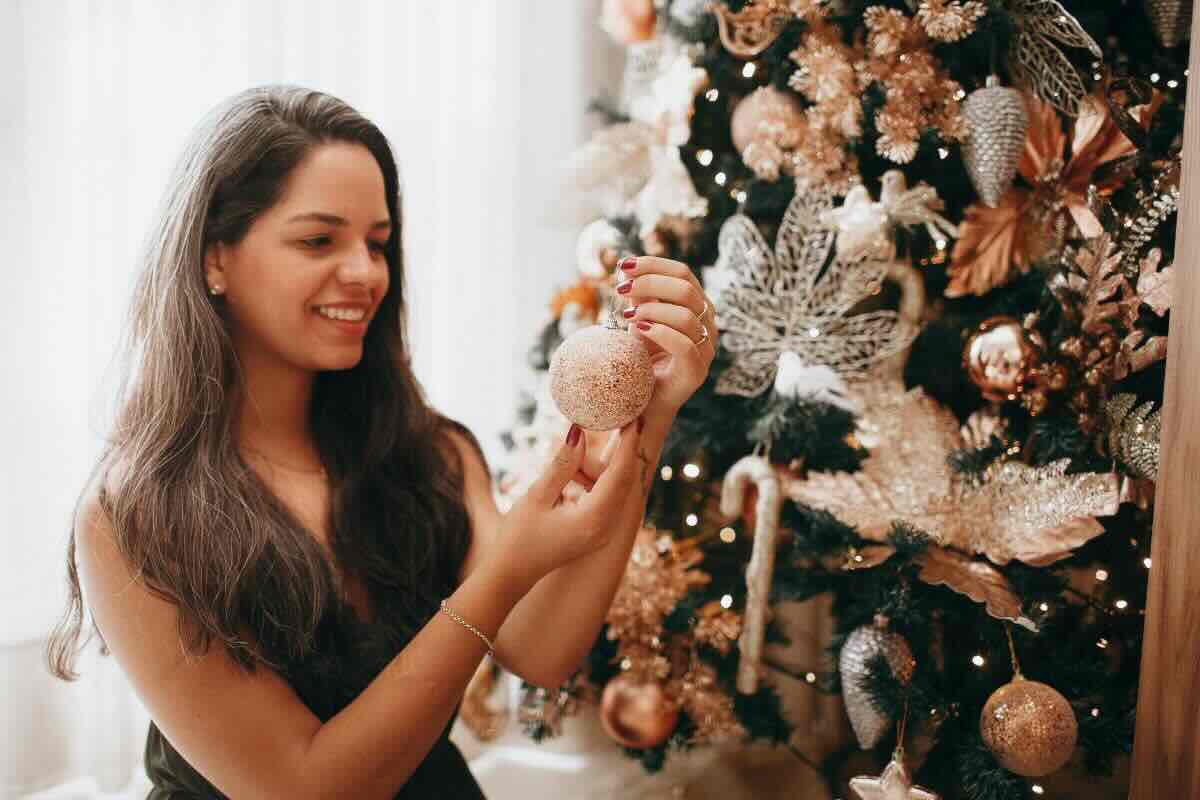 Donna con pallina bianca davanti all'albero di Natale