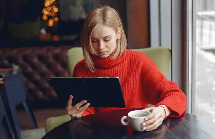 donna seduta al bar con un tablet
