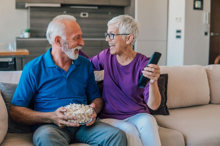 Coppia sul divano, lui pop corn, lei telecomando in mano